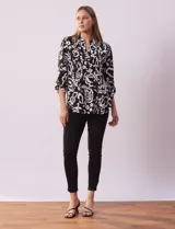 Blusa de gasa estampada en blanco y negro, marca Zac & Rachel. Cuello a la base con escote en V y abertura central con botones. Delantera con detalle plisado. Largo de manga regulable con presilla y botón.