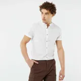 Camisa blanca de lino con cuello mao, manga corta con dobladillo y cierre frontal con botones.