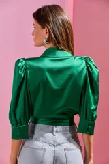 Blusa cruzada de satén color verde esmeralda, con mangas tres cuartos abullonadas y lazo lateral.