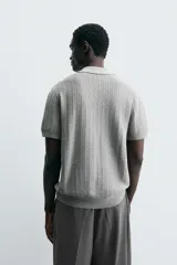 Polo gris de punto con textura, corte regular, cuello solapa y cierre frontal con botones.