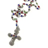 Collar tipo rosario con cadena plateada y cuentas de cristal de colores. Dije de cruz plateada con incrustaciones de cristales de colores.