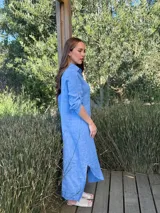 Vestido camisero largo de lino blanco, con corte en la cintura, abertura lateral y botones de nácar.