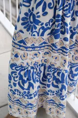Vestido largo de corte holgado con estampado floral en tonos azul y blanco. Tiene cuello en V, mangas largas y falda con volantes.