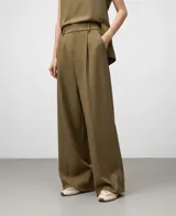 Pantalón de vestir ancho color caqui, con pinzas delanteras, trabillas en la cintura y bolsillos laterales y de vivo traseros.