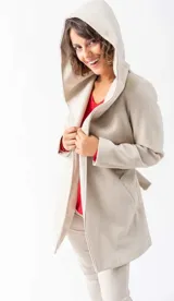Saco de paño color nude, de corte recto, con capucha amplia, bolsillos laterales y lazo para ajustar en la cintura.