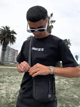 Bandolera negra con correa ajustable y cinco bolsillos.