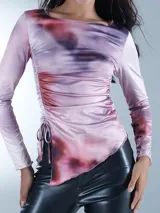 Blusa de manga larga con diseño estampado en tonos morados y rosas, con detalles de fruncido en los laterales.