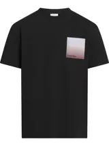 Remera negra de algodón con cuello redondo y manga corta. Presenta un diseño cuadrado con efecto ombré en tonos blanco, rosa y naranja, con el logo de Calvin Klein estampado en el centro.