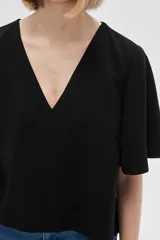 Blusa color crema de viscosa con escote en V y mangas cortas acampanadas.