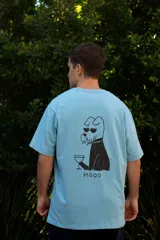 Remera celeste de algodón con estampado en la espalda de un perro con gafas de sol y un trago en la mano, con la palabra "MOOD" debajo.