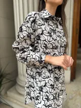 Camisa amplia blanca con estampado floral en negro, de corte suelto y manga larga.