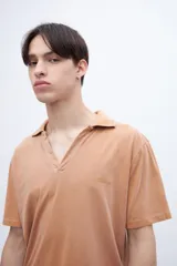 Chomba color ocre, de algodón lavado, con cuello clásico y bordado en el pecho.