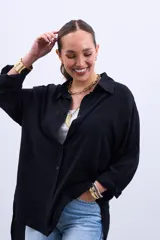 Camisa negra de corte amplio, con cuello clásico y mangas largas.