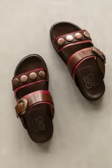Sandalias bajas de cuero marrón con doble tira, una lisa con apliques metálicos y otra con textura símil reptil y hebilla metálica.