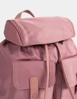 Mochila de tela color lila, con solapa con broche y tira de ajuste, doble bolsillo frontal con broche y pouch con charm lateral en forma de cartera.