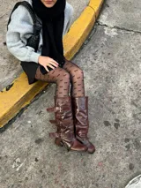 Borcegos de cuero color chocolate con efecto gastado. Caña alta con tres correas con hebillas plateadas. Taco bajo. Industria Argentina.