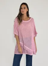 Blusa rosa de lino y algodón, de corte amplio, con cuello redondo y mangas cortas. Presenta detalle de volados en el ruedo y terminaciones desflecadas.