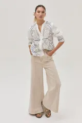 Camisa blanca de lino con bordados florales en tonos beige y azul.