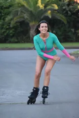 Traje de baño enterizo de lycra verde con mangas largas fucsia y cierre frontal con cremallera fucsia.