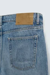 Pantalón de jean celeste de corte recto, con cinco bolsillos y cierre frontal con botones.
