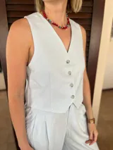 Chaleco sastrero sin mangas, color celeste claro, con escote en V y cierre frontal de tres botones.