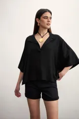 Blusa negra de lino con cuello polo y mangas cortas amplias.
