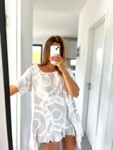 Túnica beige con estampado batik en blanco, de corte holgado, mangas cortas y ruedo irregular con volados.