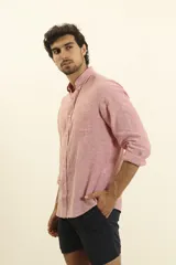 Camisa azul marino de lino y algodón, con cuello abotonado, manga larga con puños enrollados, bolsillo de parche en el pecho y cierre frontal con botones.