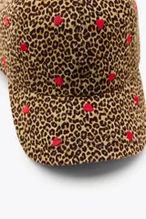Gorra de sarga con estampado animal print y corazones bordados en rojo.