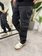 Pantalón de jean negro gastado, corte baggy con bolsillos cargo laterales.