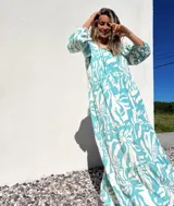 Vestido largo de corte amplio, con estampado abstracto en tonos verde agua y crudo. Tiene escote en V con lazos y mangas largas abullonadas.