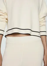 Pantalón palazzo color crema de tejido de punto fino, con cintura elástica y bandas laterales negras en contraste.