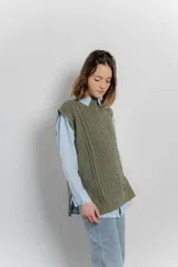 Chaleco de punto color crema con cuello alto y diseño de trenzas.