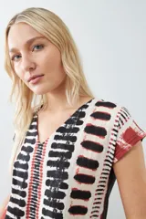 Blusa de manga corta con estampado abstracto en tonos beige, negro y rojo.