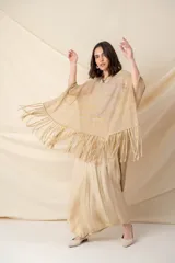 Poncho artesanal color beige con hilos de lurex dorados y terminación de flecos. Diseño irregular, más corto adelante que atrás.