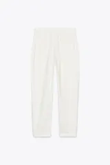 Pantalón color beige de tiro medio con cintura elástica ajustable con cordones, bolsillos delanteros y falsos bolsillos de vivo en la espalda. El bajo es ajustable con botón a presión.