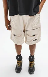 Bermuda color beige con cintura elástica, cordón de ajuste y cinturón negro con hebilla plástica. Tiene bolsillos delanteros y bolsillos cargo con solapa.