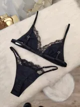 Conjunto de lencería negro, compuesto por un corpiño triangular de algodón con detalles de encaje y una tanga de algodón con detalles de encaje.