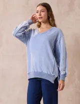 Buzo celeste de algodón con efecto lavado, escote en V, cuello, puños y ruedo acanalados y tajos laterales.