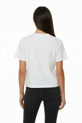 Remera de algodón negra, manga corta y cuello redondo, con un diseño abstracto de líneas curvas formadas por apliques de studs plateados en el pecho.