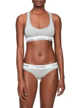 Bralette deportivo Calvin Klein Modern Cotton, color gris, sin relleno ni forro, con espalda cruzada y banda inferior elástica blanca con logo de la marca.