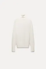 Jersey negro de punto liso con cuello alto, manga larga y detalle de botones dorados en los puños.
