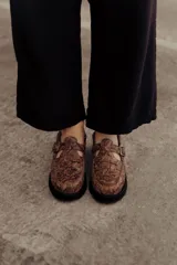 Zuecos de cuero con estampado snake, hebilla lateral metálica, puntera cuadrada y base robusta.