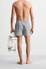 Short de baño con textura seersucker a rayas verticales azul marino y blanco. Tiene cintura elástica ajustable con cordón, bolsillos frontales y traseros, aberturas laterales en el bajo y forro interior.