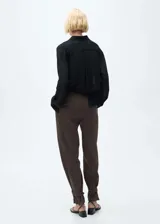 Pantalón marrón de corte wide leg, tiro medio, con cierre de cremallera, gancho y doble botón.