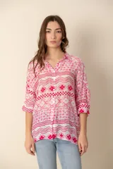 Camisa celeste con estampado de soles, lunas, flores y tortugas en tonos verdes, amarillos y naranjas.
