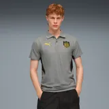 Polo Puma gris con cuello clásico, tapeta de dos botones y mangas cortas con puños negros. Logo de Puma bordado en amarillo en el pecho izquierdo y escudo del Club Atlético Peñarol bordado en el pecho derecho. Paneles laterales negros.