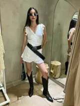 Vestido corto color crema, de lino, con escote en V cruzado, mangas cortas con volados y falda con volados.