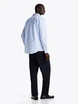 Camisa celeste con rayas verticales, de corte regular, cuello abotonado, mangas largas con puños abotonados y logo de la marca bordado en el pecho.