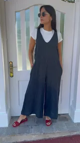 Mono largo negro de lino con breteles finos ajustables que se atan en la espalda y bolsillos laterales.